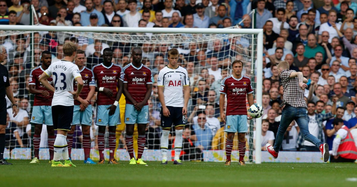 A supporter runs onto the pitch and kicks the ball set up for a Tottenham Hotspur's free kick against West Ham United during their English Premier League soccer match at Upton Park, London, Saturday, Aug. 16, 2014.